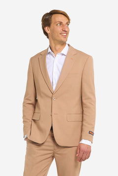 Image with light grey background and man wearing Dark Sand men’s suit and white shirt. Suits consists of blazer and pants. Man looking to the side.