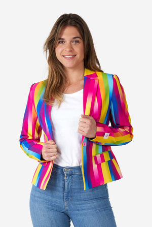Image of woman wearing vertically striped rainbow colored women's blazer , white shirt and blue jeans. She is holding the sides of the blazer.