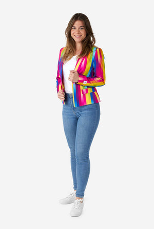 Image of woman wearing vertically striped rainbow colored women's blazer , white shirt, white shoes and blue jeans. She is holding the sides of the blazer. Full body image.