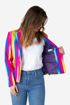 Image of woman wearing vertically striped rainbow colored women's blazer , white shirt and blue jeans. She is holding one side of the blazer open, showing the purple lining.