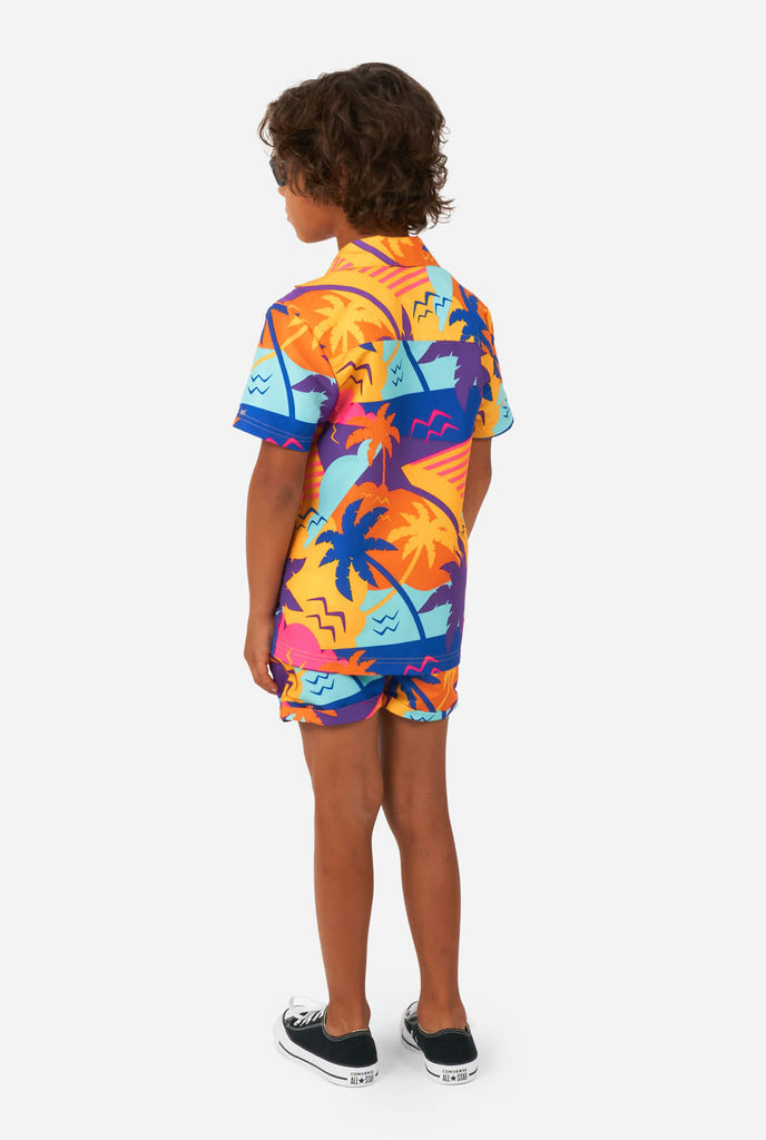Boy wearing colorful palm summer set, consisting of shorts and shirt, view from the back