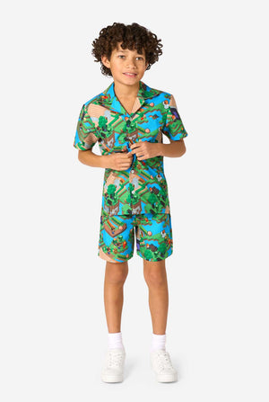 A young boy wearing a colorful summer outfit featuring a Minecraft Overworld print, showcasing pixelated landscapes, characters, and elements from the iconic game. The short-sleeve shirt and matching shorts highlight a vibrant design inspired by the Minecraft universe. Full body image.