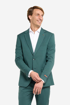 Image with light grey background and man wearing dark green men’s suit and white shirt. Suits consists of blazer and pants. Man looking side ways.