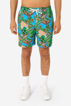 A man wearing a colorful summer outfit featuring a Minecraft Overworld print, showcasing pixelated landscapes, characters, and elements from the iconic game. The short-sleeve shirt and matching shorts highlight a vibrant design inspired by the Minecraft universe. Close-up shorts