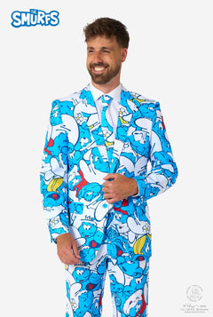 Smiling man wearing a colorful Smurfs men's suit with an all-over cartoon print in blue, white, red, and yellow, including a matching tie and white shirt, standing against a plain background.