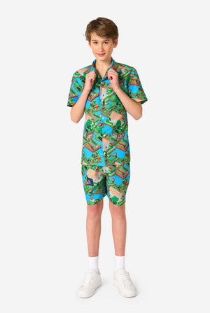 A Teen boy wearing a colorful summer outfit featuring a Minecraft Overworld print, showcasing pixelated landscapes, characters, and elements from the iconic game. The short-sleeve shirt and matching shorts highlight a vibrant design inspired by the Minecraft universe. Full body image