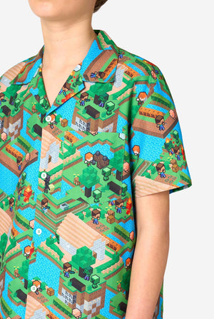 A Teen boy wearing a colorful summer outfit featuring a Minecraft Overworld print, showcasing pixelated landscapes, characters, and elements from the iconic game. The short-sleeve shirt and matching shorts highlight a vibrant design inspired by the Minecraft universe. Focused on the chest