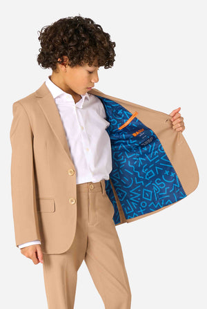 Kid wearing a stylish light brown/ beige suit with a white dress shirt, looking away from the camera. Perfect formal outfit for boys' special occasions, weddings, and parties. Holding one side of the jacket open.