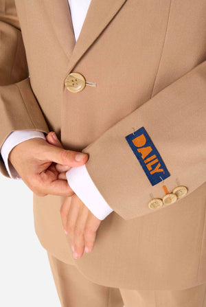 Kid wearing a stylish light brown/ beige suit with a white dress shirt, looking away from the camera. Perfect formal outfit for boys' special occasions, weddings, and parties. Sleeve close up.