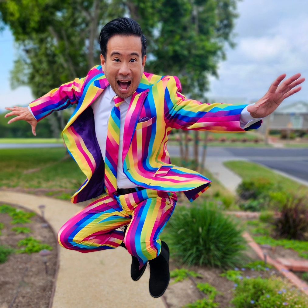 Guy in a opposuits rainbow glaze suit is jumping with his mouth wide open