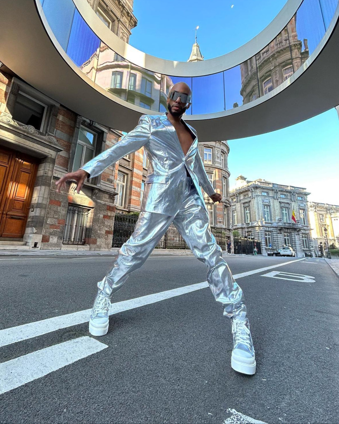 Person in a silver reflective outfit posing on a city street.