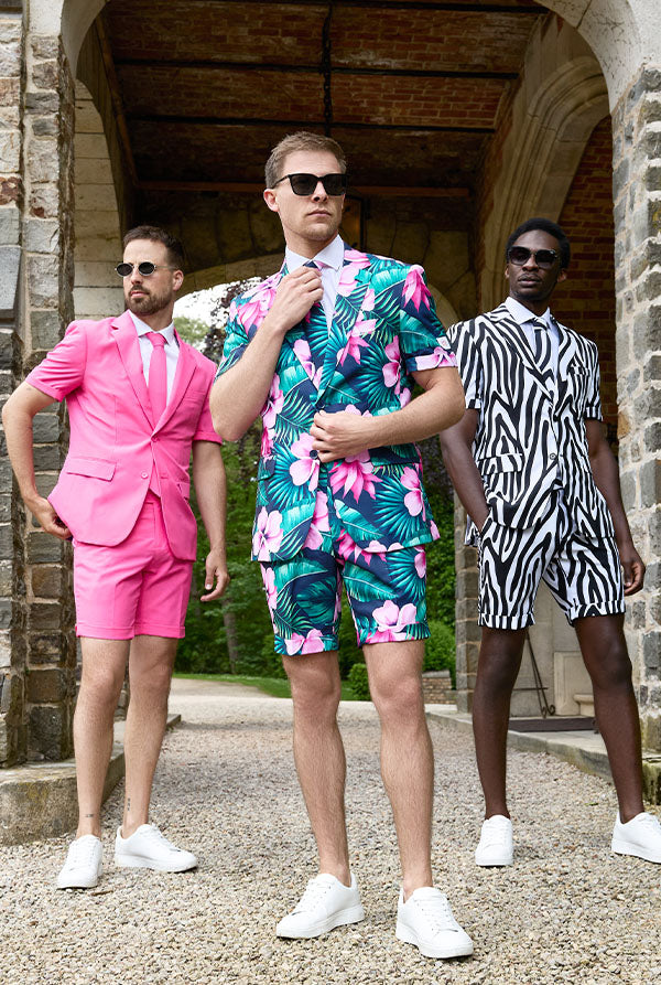 Three men in colorful suits standing in front of a stone building.