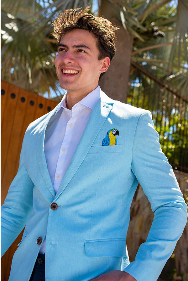 Man wearing a light blue suit with a colorful pocket square outdoors.
