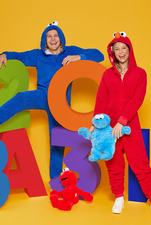 Two people in colorful Sesame Street onesies against a yellow background