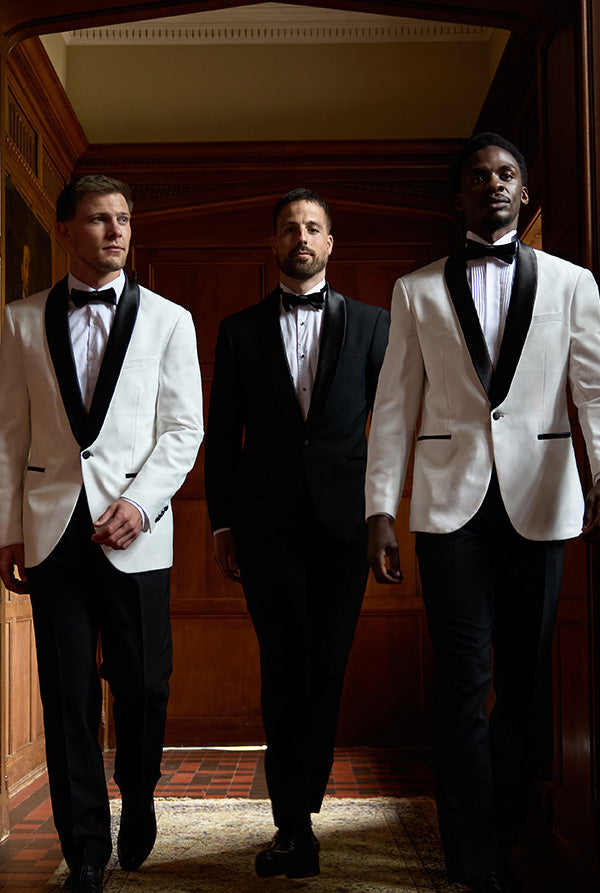 Three men in formal suits standing in a hallway.