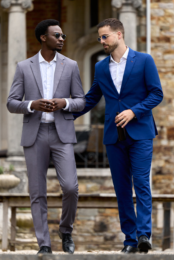 Two men in suits standing outdoors with a stone building in the background