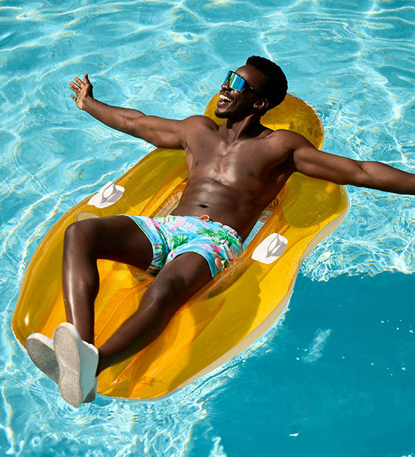 Man relaxing on a yellow inflatable raft in a pool