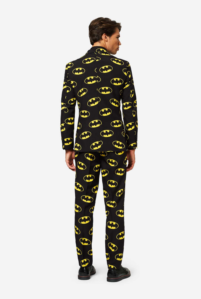 Man wearing Black suit with Yellow Batman logos.