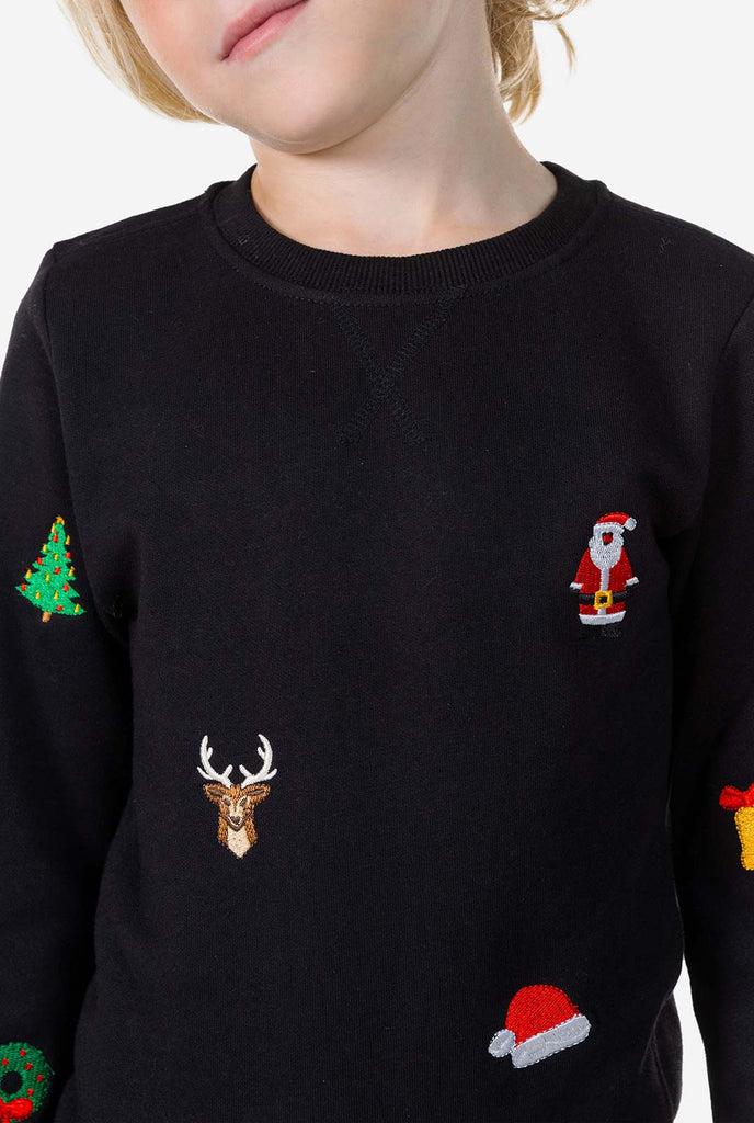 Kid wearing black Christmas sweater with Christmas icons