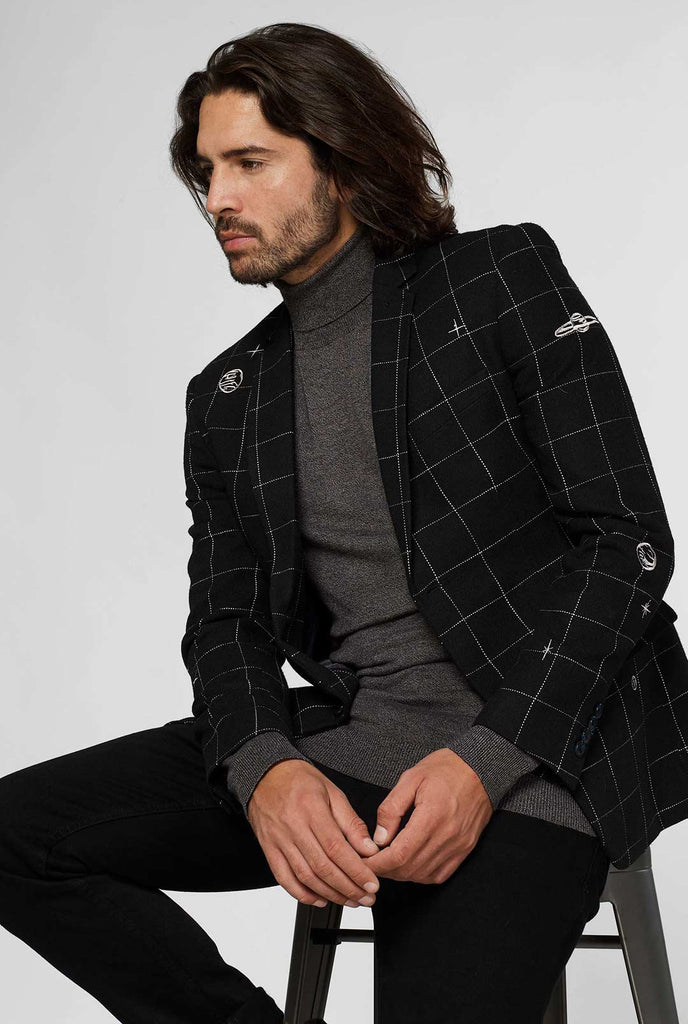 Black casual blazer with white grid pattern worn by man sitting on stool