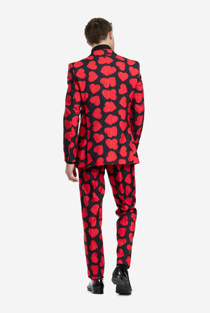 Person wearing a red and black heart-patterned suit on a white background