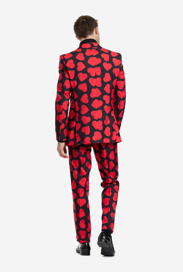 Person wearing a red and black heart-patterned suit on a white background