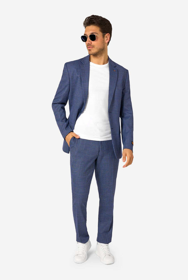 A men wearing a navy and blue checkered suit with a white dress shirt. The suit has a modern fit with two buttons and flap pockets. He stands against a plain white background. Full body image, wearing sunglasses