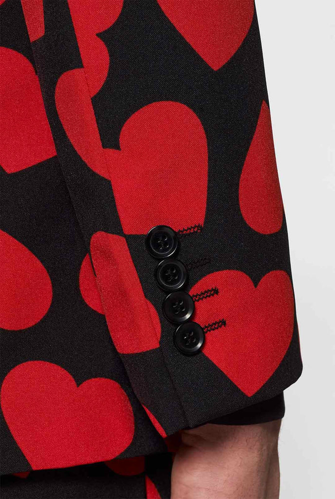 Man wearing black suit with red hearts print
