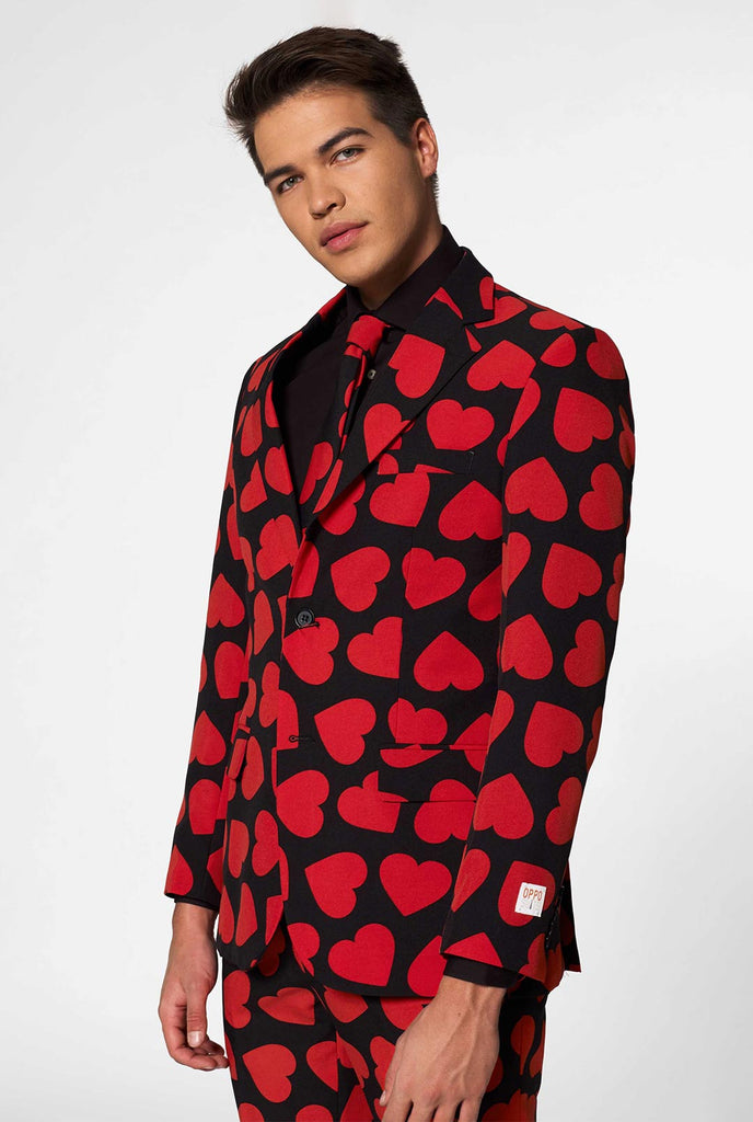 Man wearing black suit with red hearts print