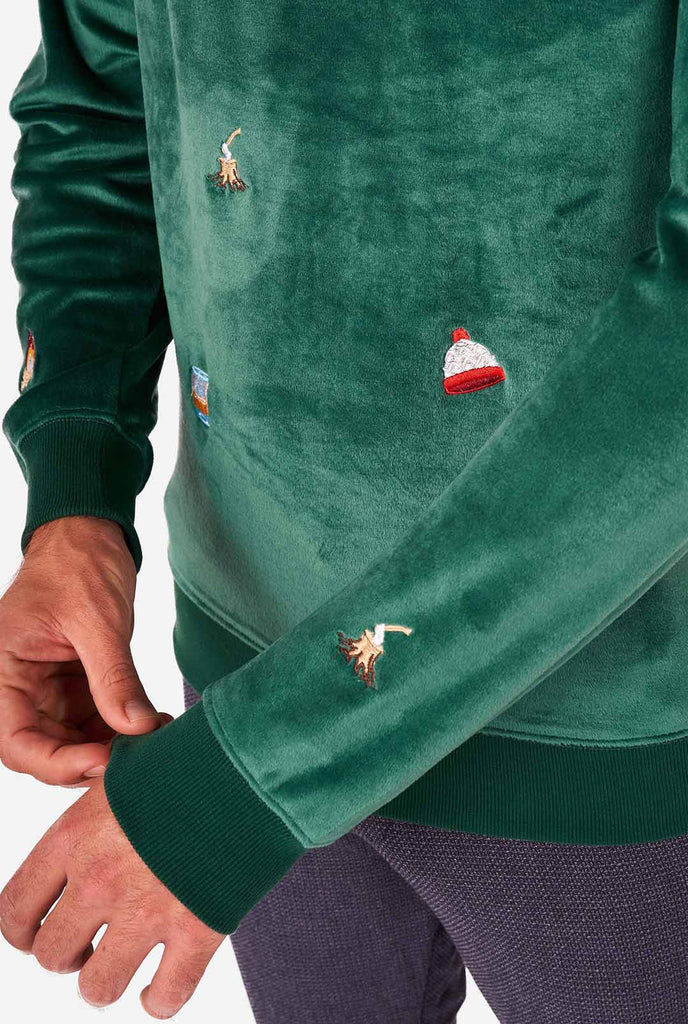 Man wearing velvet green Christmas sweater with Christmas icons