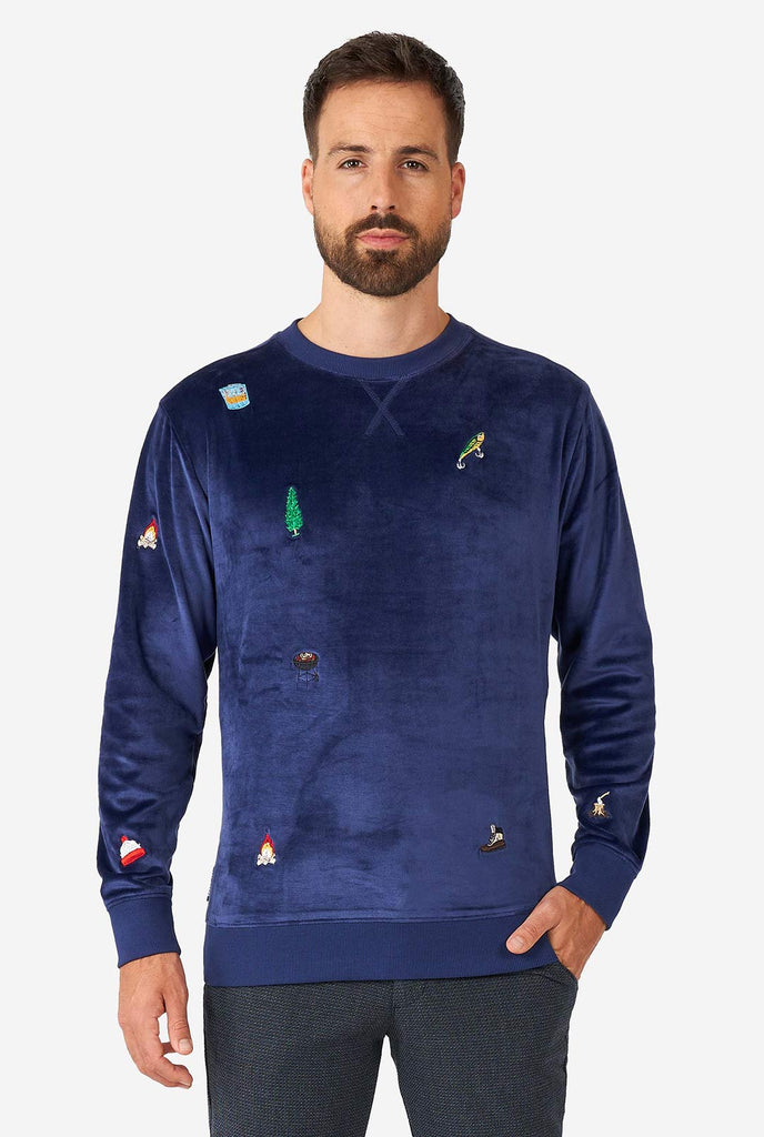 Man wearing velvet blue Christmas sweater with Christmas icons