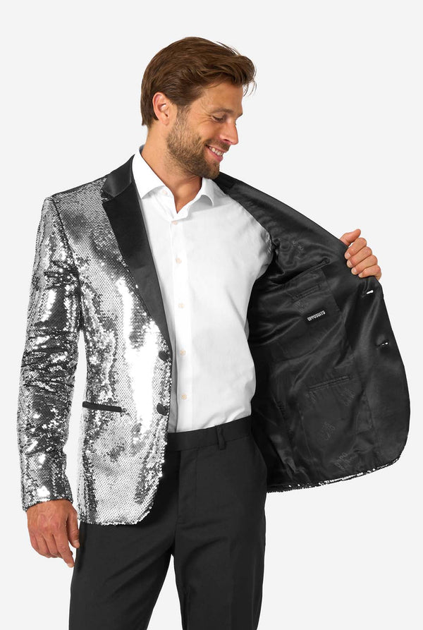 Man holding a silver sequin blazer over a black one against a white background