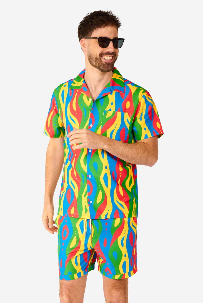 Man wearing colorful summer set, consisting of shirt and shorts.