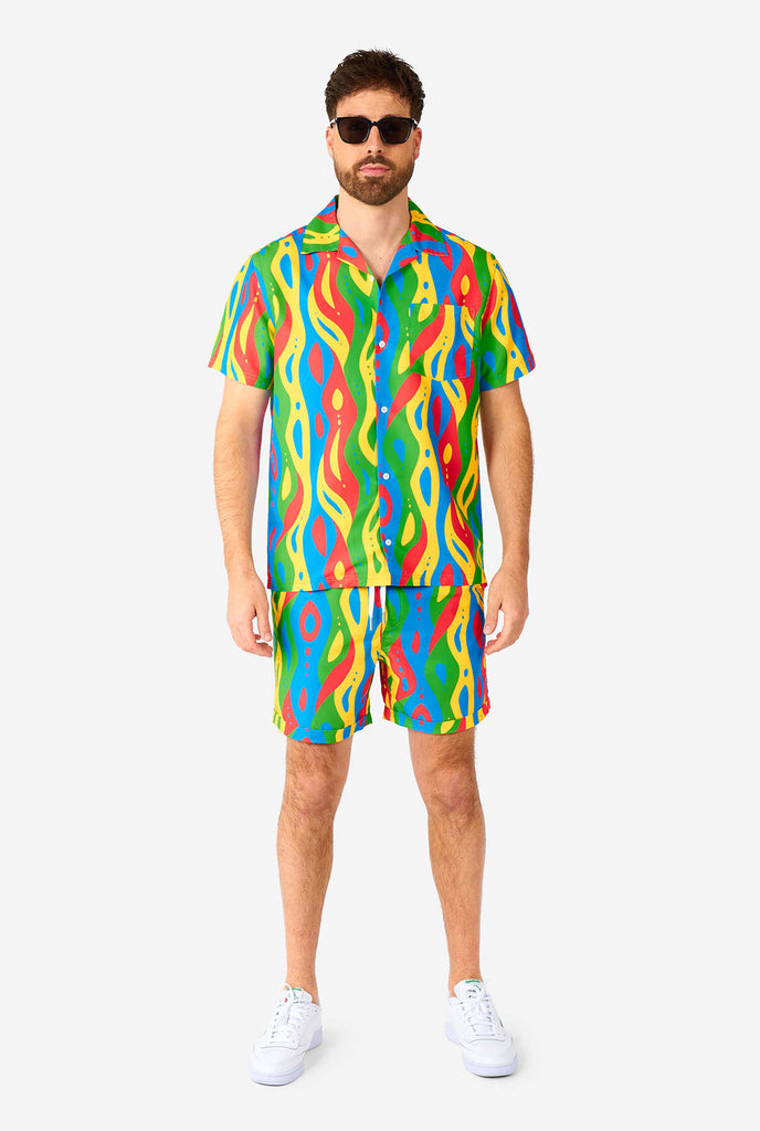 Man wearing colorful summer set, consisting of shirt and shorts.