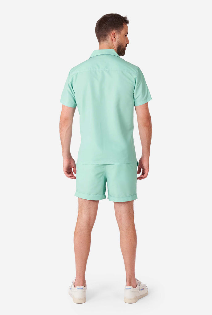 Man wearing green summer set, consisting of short sleeve shirt and shorts.