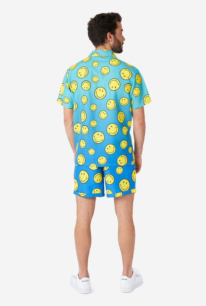 Man wearing blue summer set, consisting of shorts and shirt, with Smiley print