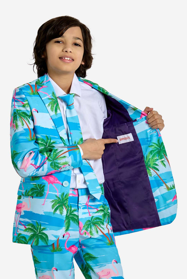 Child wearing a colorful suit with palm tree and flamingo pattern, pointing to the pocket.