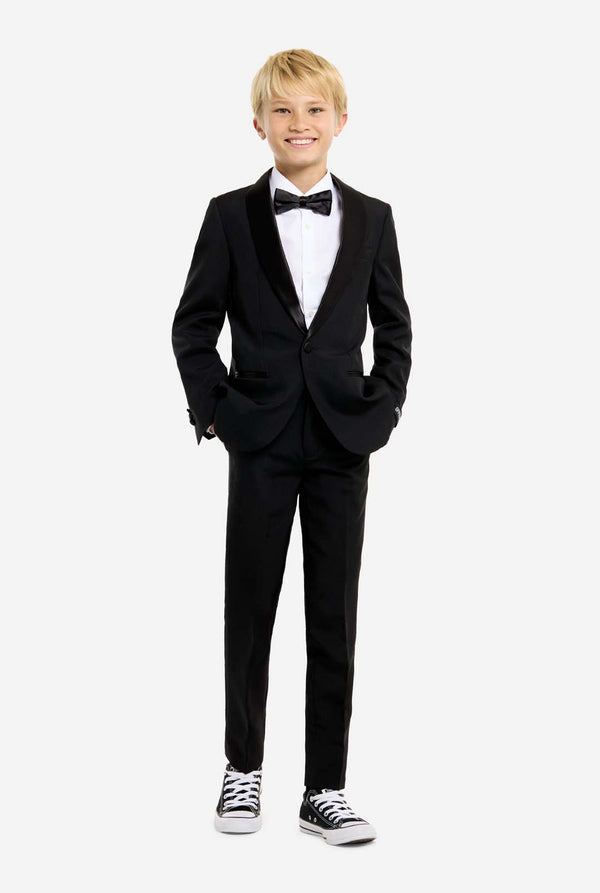 Young boy wearing a black tuxedo with a white shirt and black bow tie on a white background.