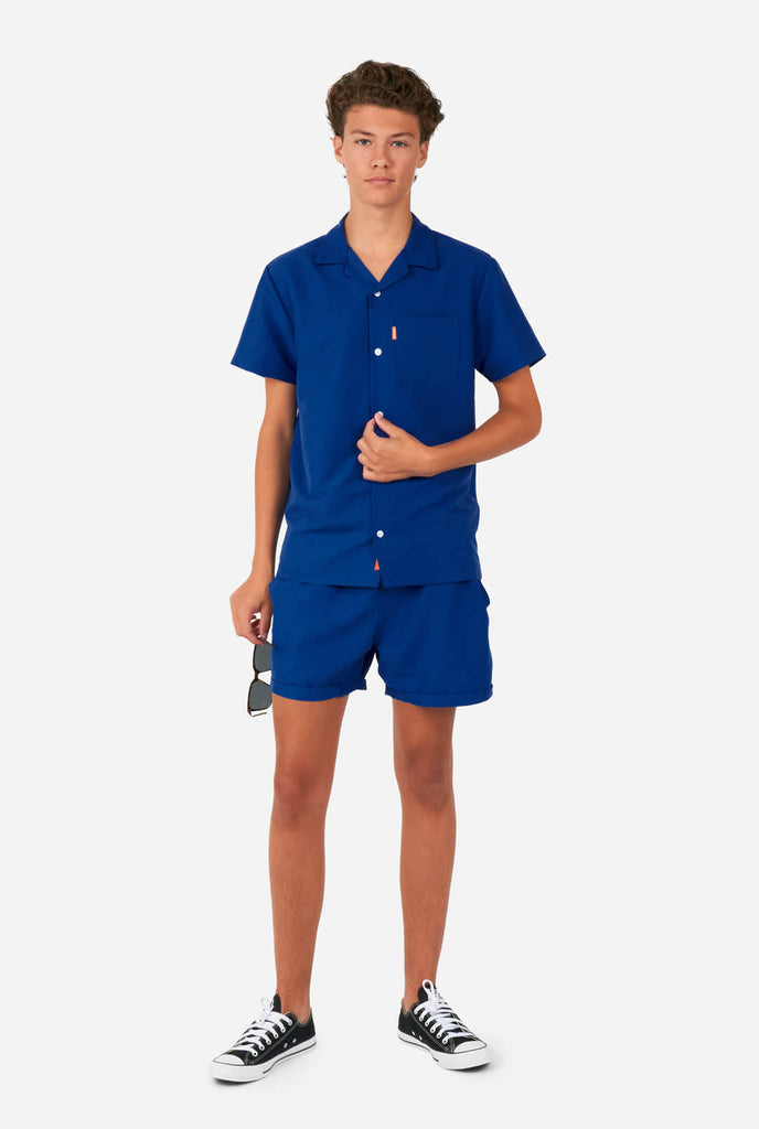 Teen wearing blue summer set, consisting of shirt and short.