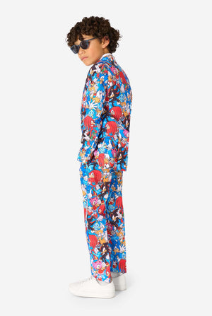 Young boy wearing sunglasses and a vibrant Sonic teen suit featuring colorful prints of Sonic the Hedgehog characters including Sonic, Knuckles, Tails, and Amy, paired with a matching tie and white shirt. Side view.