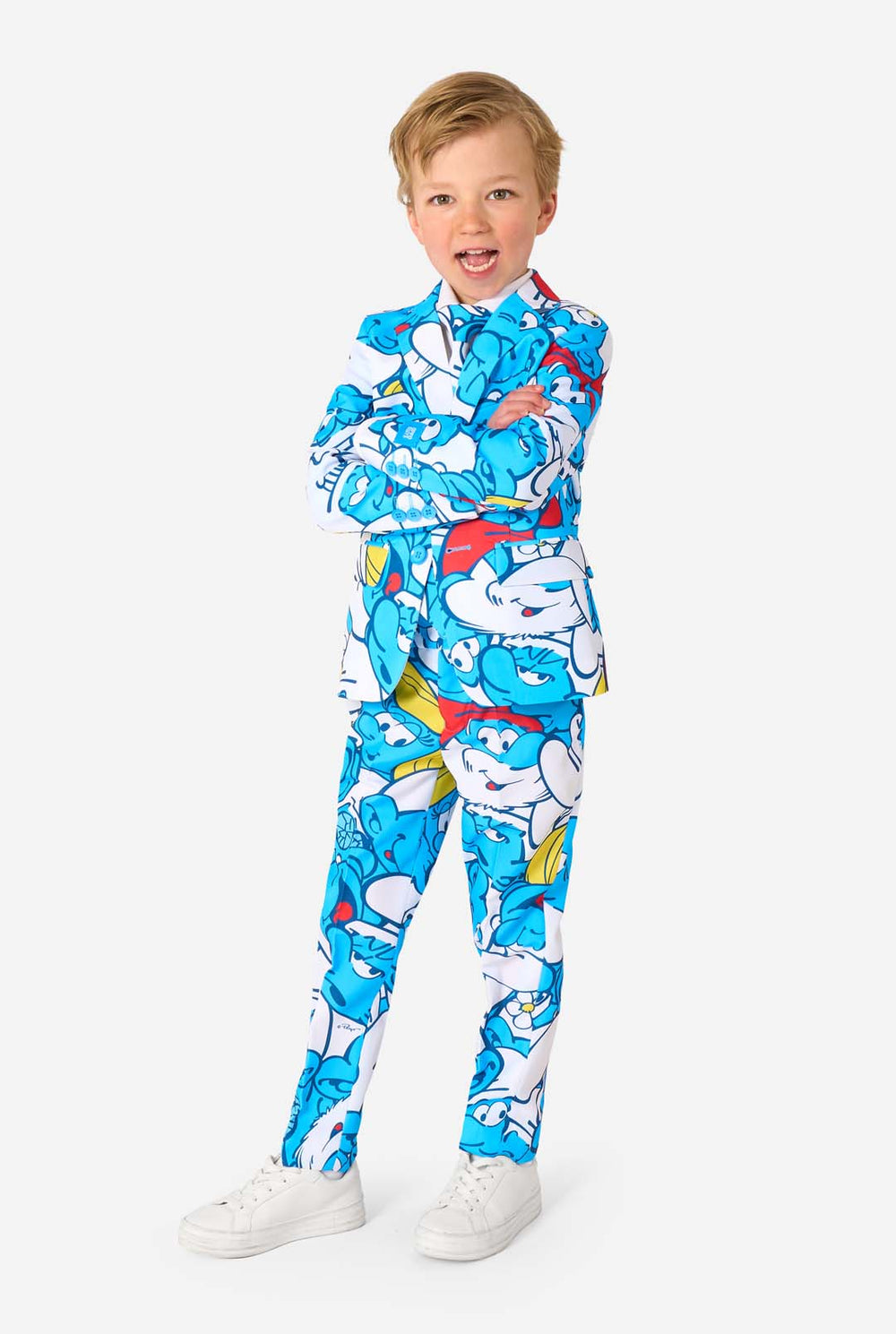 Young boy wearing a colorful Smurfs-themed kids suit featuring vibrant blue cartoon character prints, including jacket, pants, and matching tie, smiling against a plain white background.