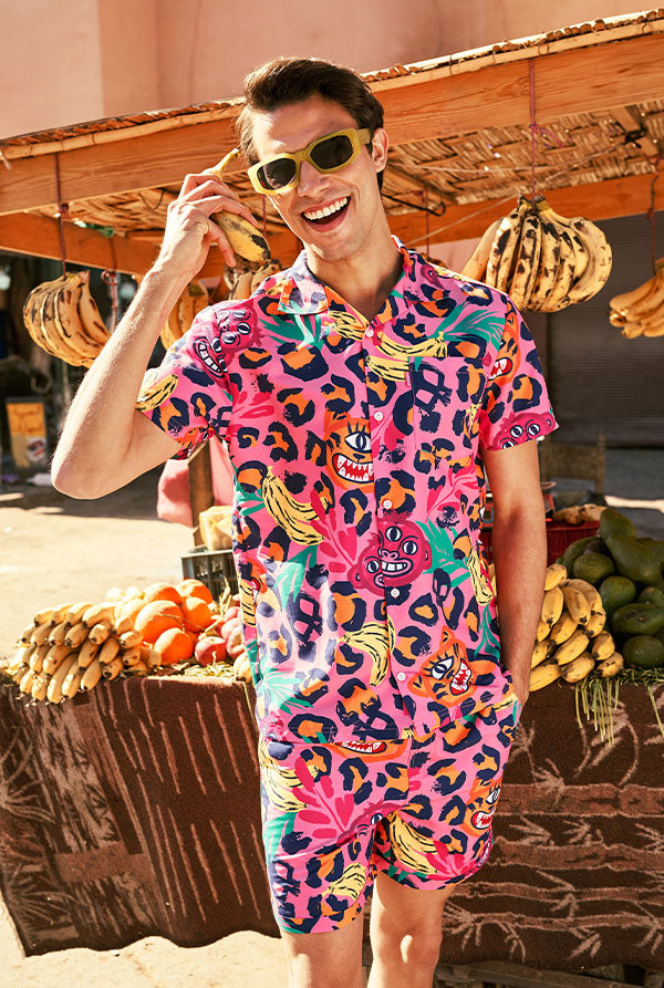 Person wearing a colorful outfit with a vibrant pattern, standing in front of a fruit stand.