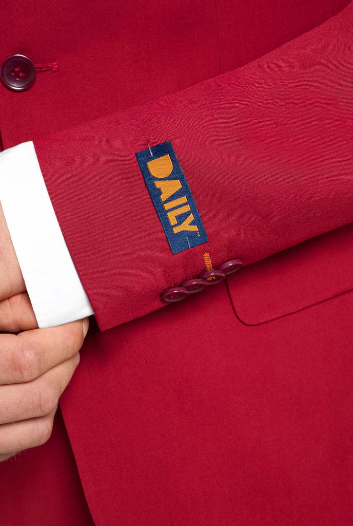 Image with light grey background and man wearing Bright Burgundy men’s suit and white shirt. Suits consists of blazer and pants. Focused on the sleeves.