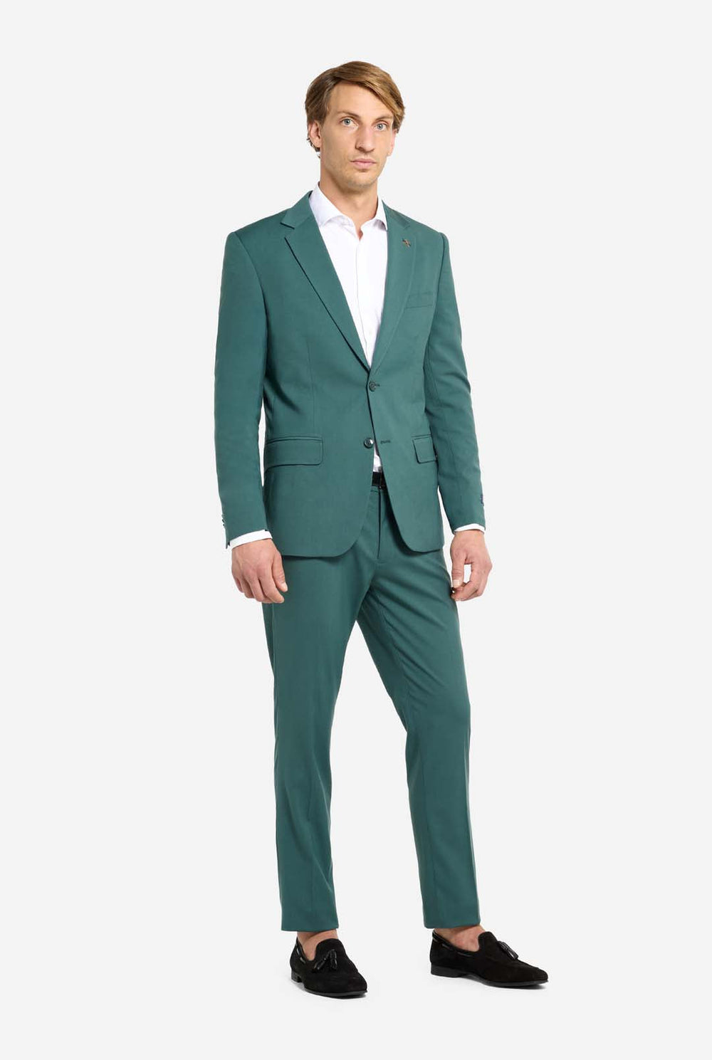 Image with light grey background and man wearing dark green men’s suit and white shirt. Suits consists of blazer and pants. Man looking side ways.