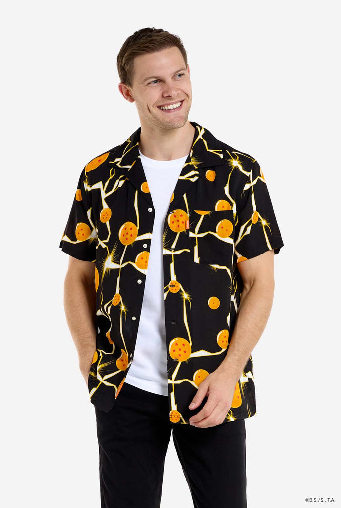 Man wearing black Hawaiian shirt with Dragon Ball Z print, showings Dragon Balls and lighting. He is also wearing a white t-shirt and black pants.