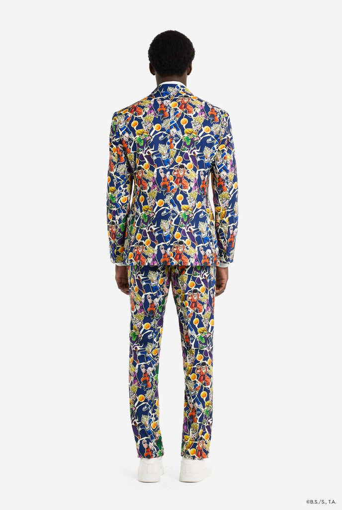 Man wearing all over print men's suit with Dragon Ball Z print which shows the Dragon Ball characters. Suit consists of Blazer, pant and tie. View from the back.