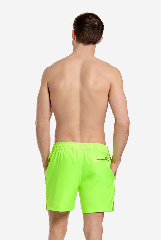 Man wearing Neon lime green swim trunks for men, view from the back