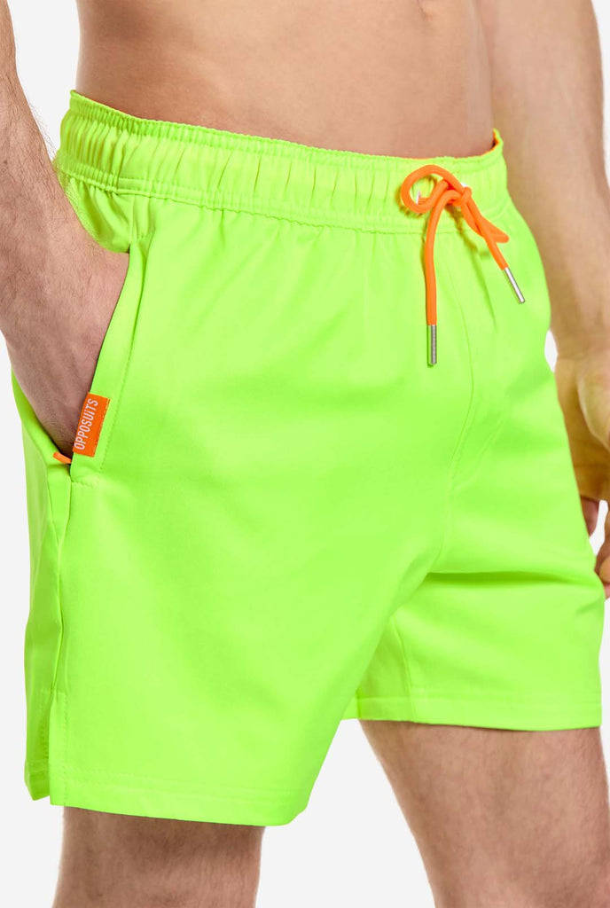 Man wearing Neon lime green swim trunks for men, close up