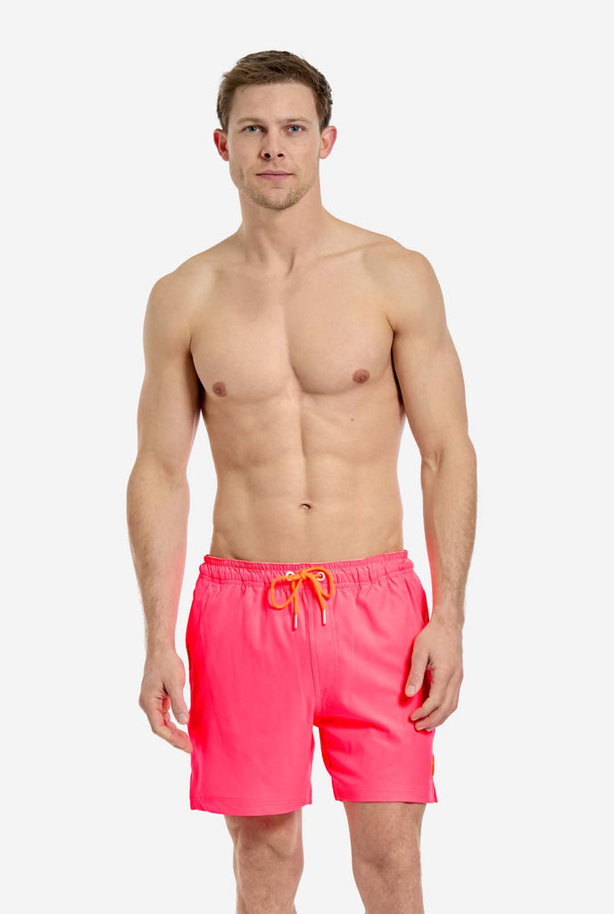 Man wearing Neon Pink Power swim trunks for men