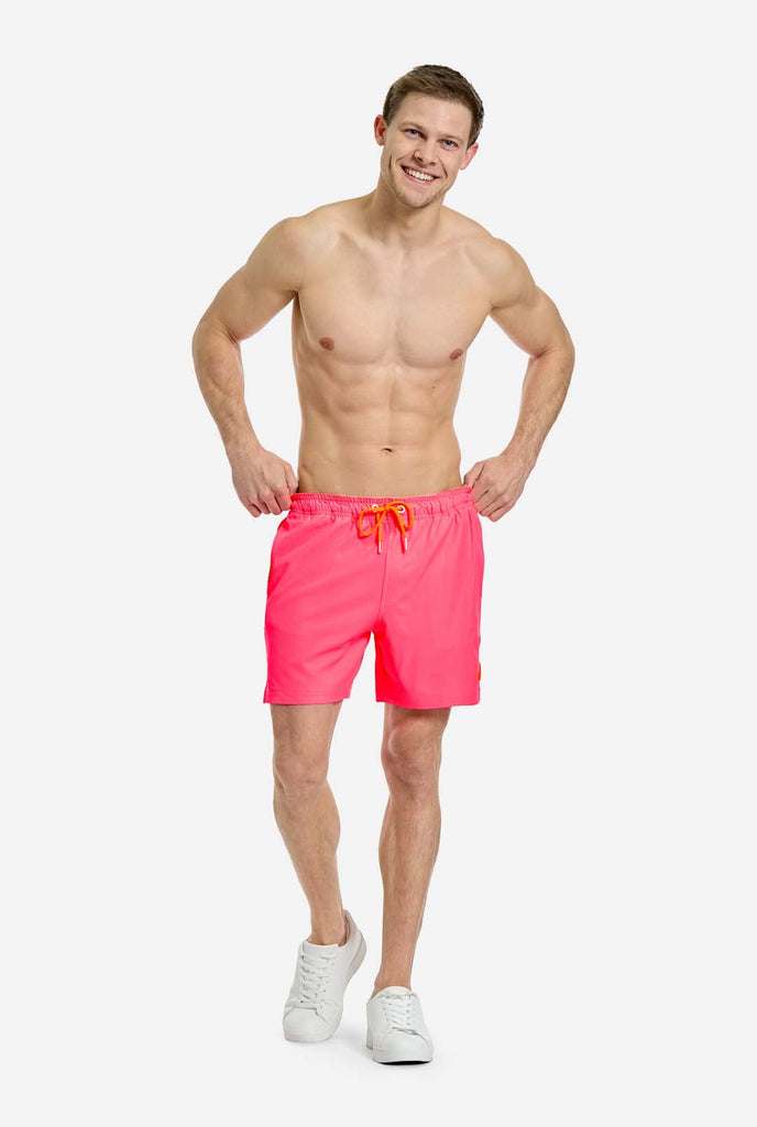 Man wearing Neon Pink Power swim trunks for men